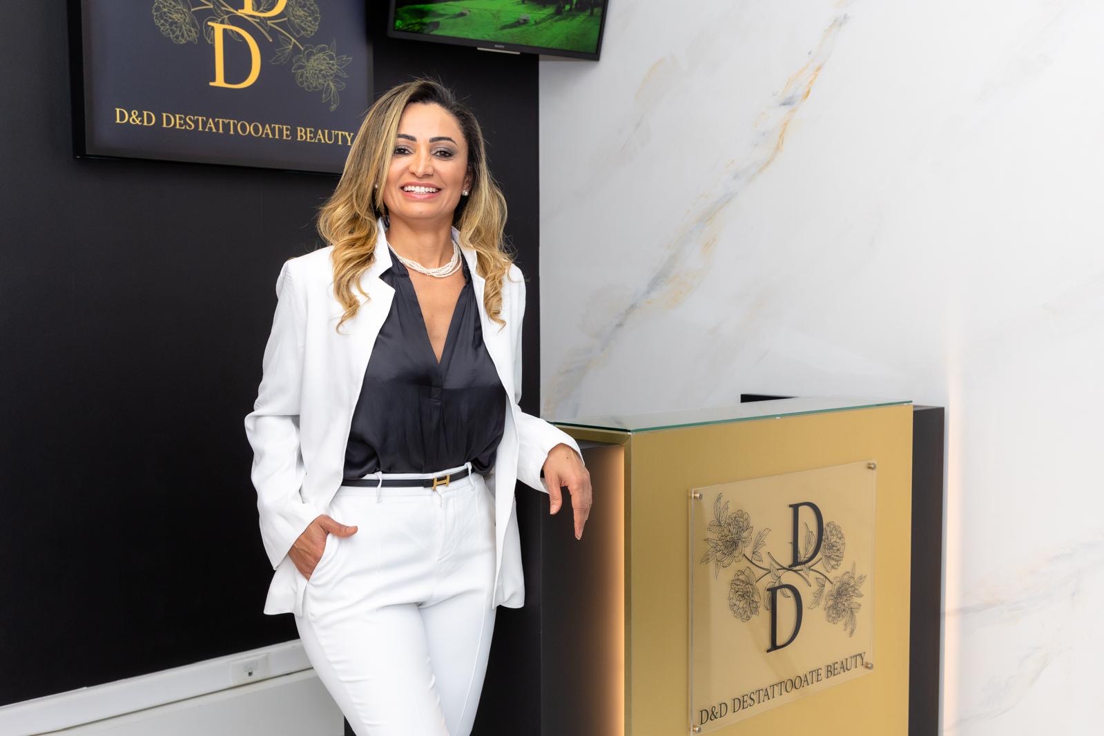 Oslaene Nunes, fundadora, sonriendo en la entrada del centro junto al mostrador dorado con el logo
